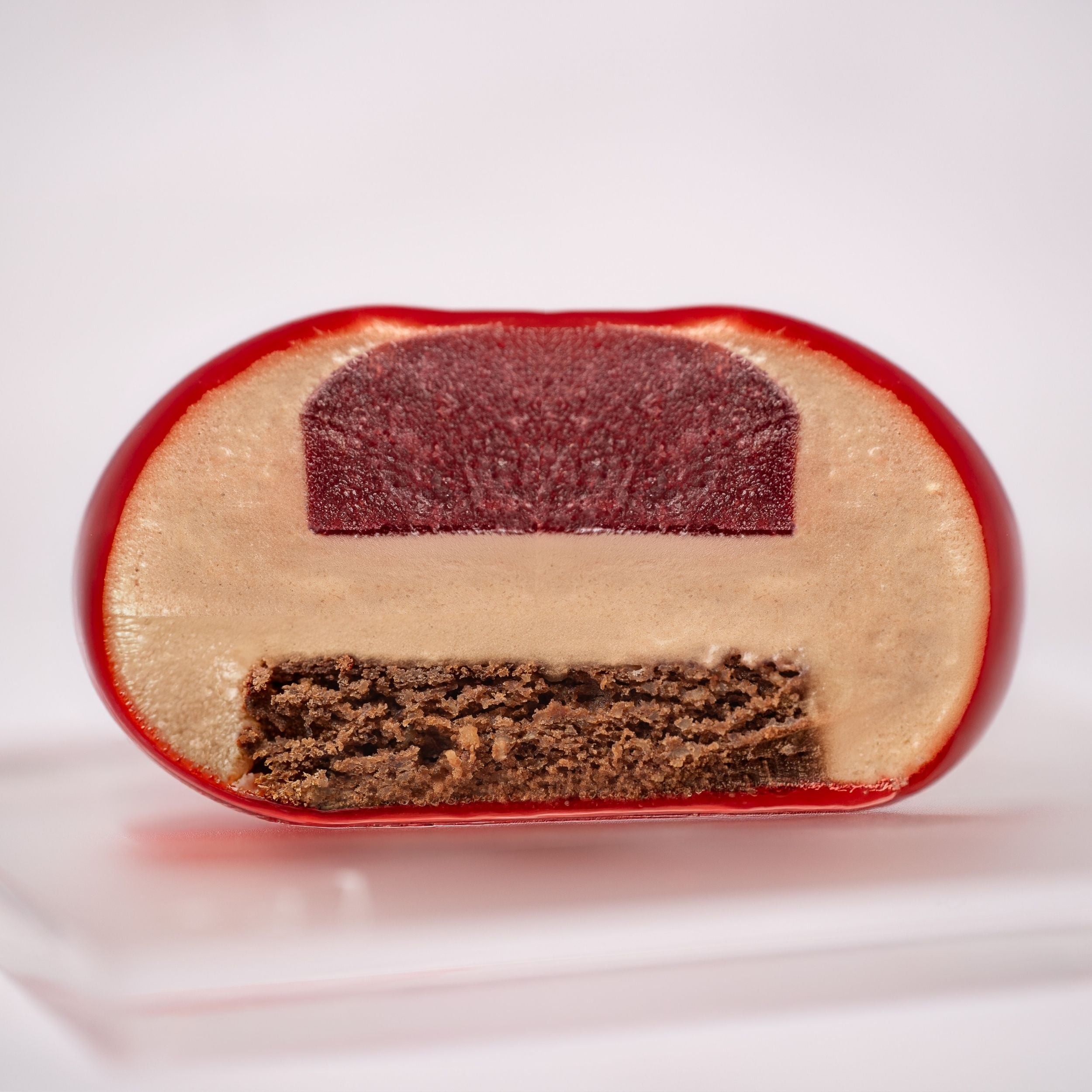 monoporzione tagliata con all'interno una gel al lampone un financie al cioccolato al latte e una muosse al cioccolato, glassata con glassa rossa 